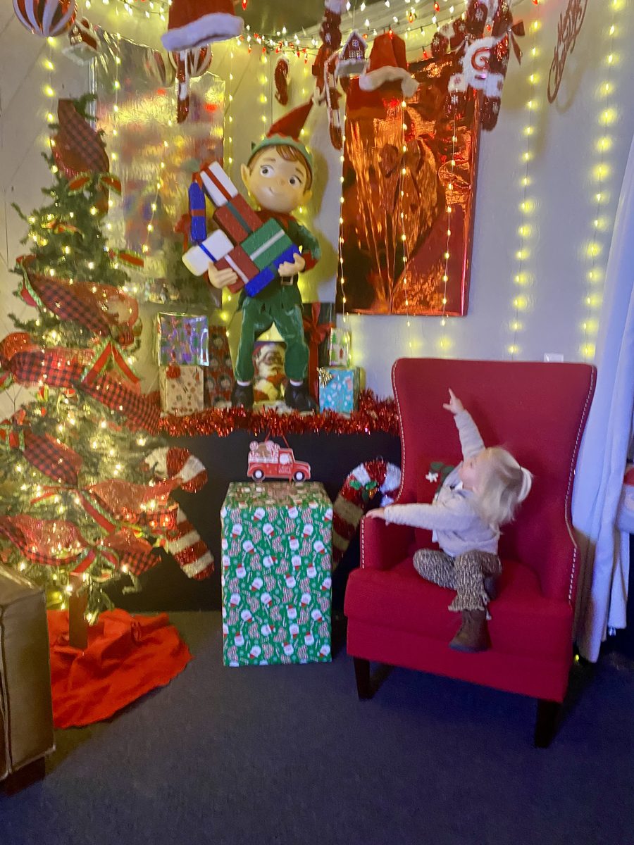 A delighted toddler pointing up at a festive elf display