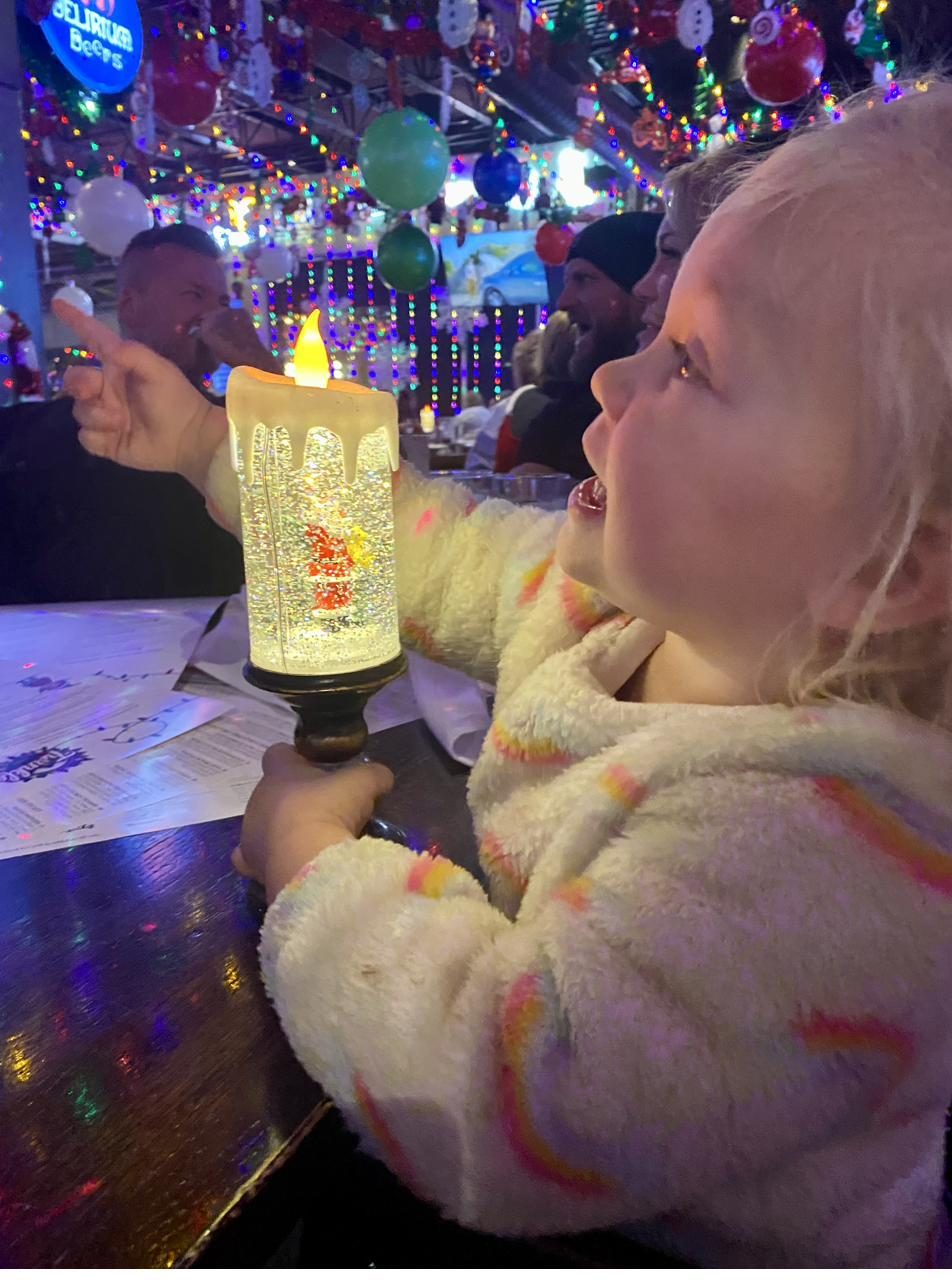 A child delighting in a glowing snow globe at the Christmas popup